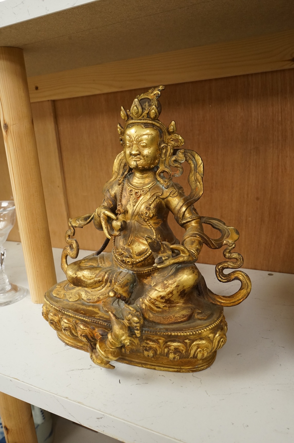 A large Sino-Tibetan gilt-bronze seated figure of Jambhala, 28cm high